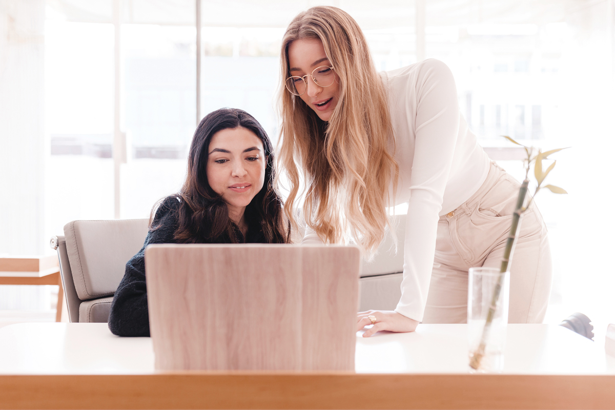 two women working together with laptop at the office